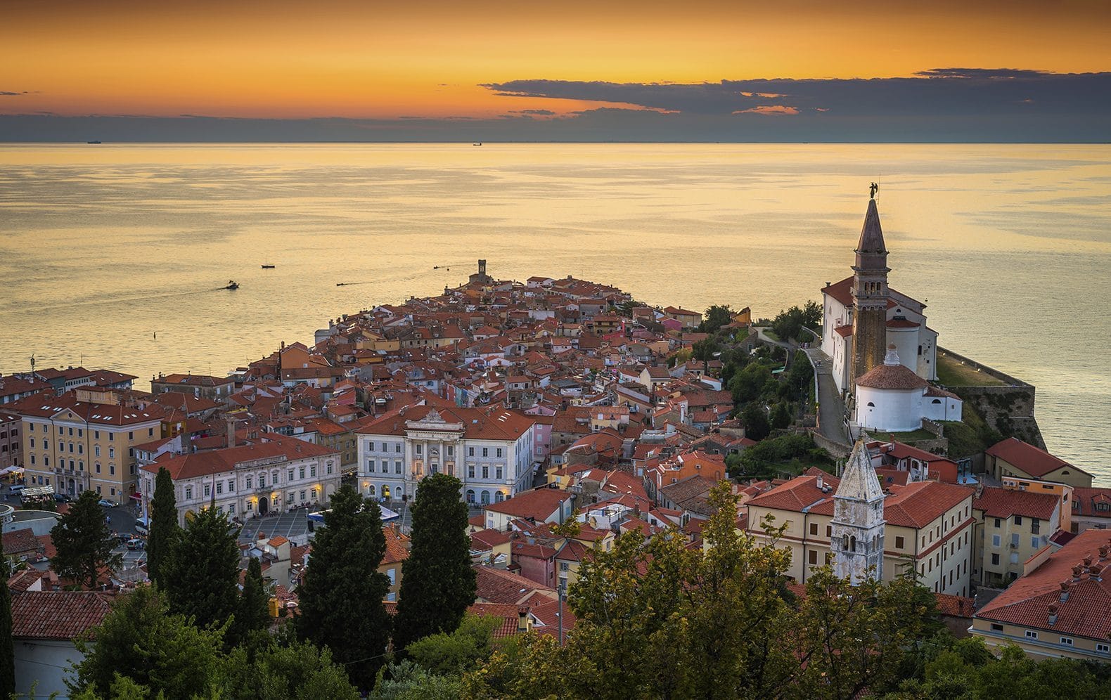 Piran old town and St George's bell tower above the Adriatic at sunset