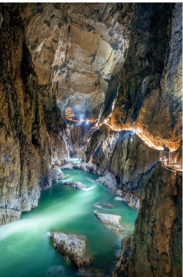 The Reka River flowing through the underground canyon of the Škocjan Caves, with the lit path along the wall